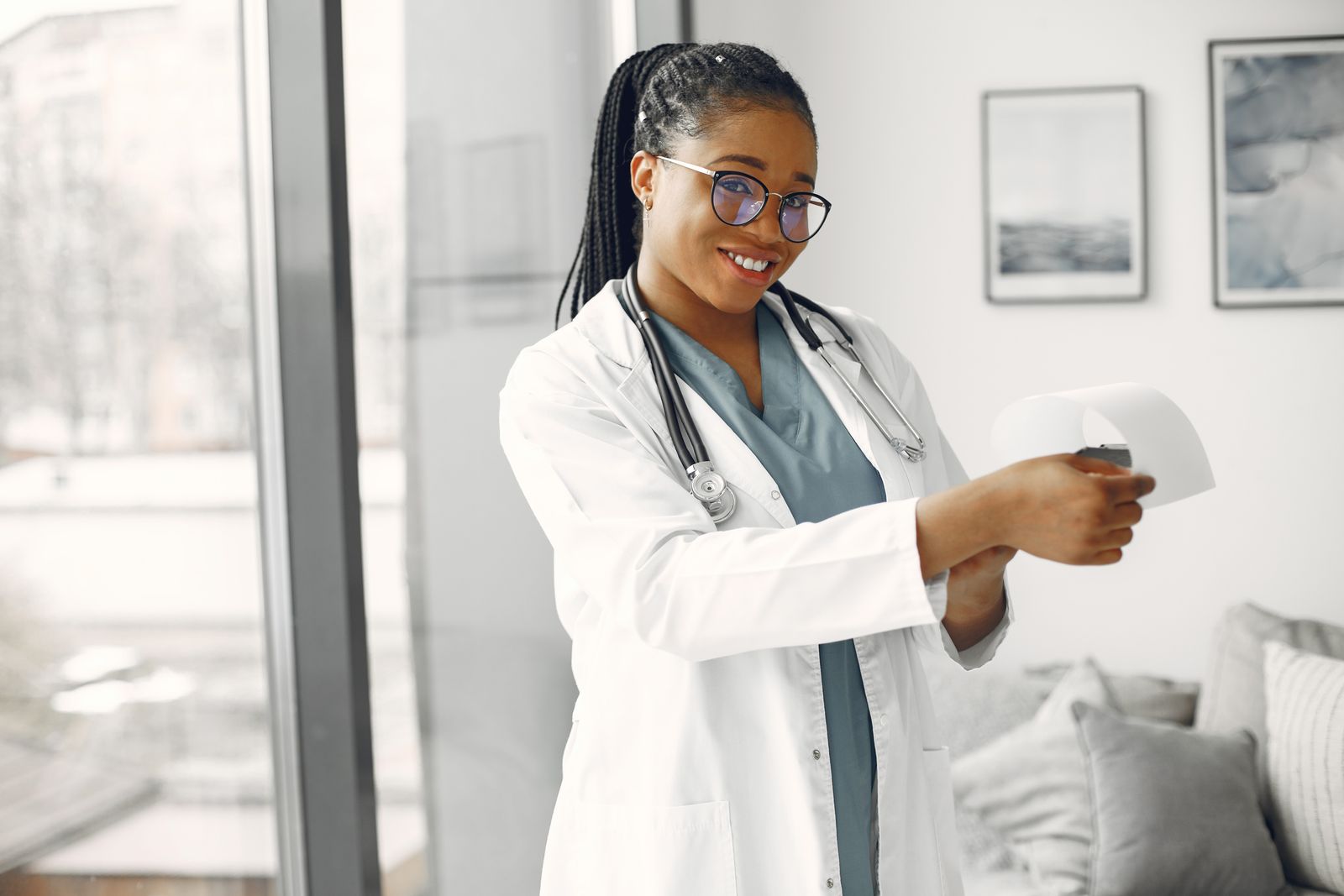 Médica sorrindo, de jaleco, com estetoscópio no pescoço.